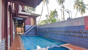 A swimming pool with a tiled deck, a staircase leading to a balcony, and a sign with instructions. - FabHotel Noronha Goaxa Inn - Nr. Calangute beach (Calangute)