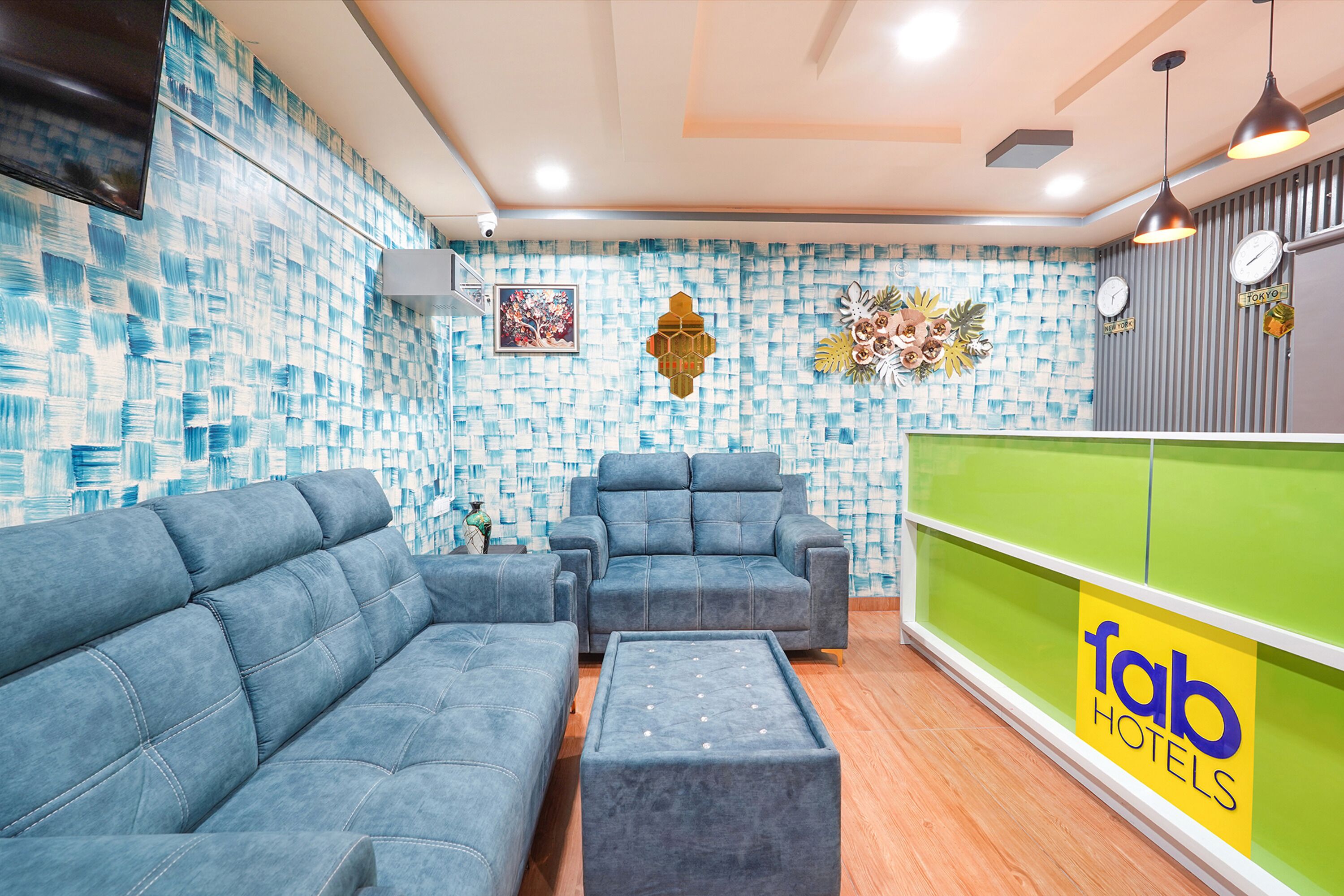 A hotel lobby with blue sofas, a green reception desk, and a patterned wall.