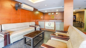 A hotel lobby with a reception desk, a sofa, and a coffee table. - Fabhotel Ample Yard (Chennai)