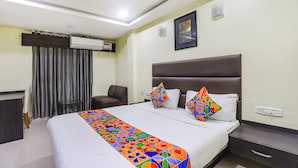 A hotel room with a large bed, a desk, a chair, an air conditioning unit, and a picture on the wall. - Fabhotel Ample Yard (Chennai)