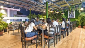 A restaurant with outdoor seating, potted plants, and string lights. - Fabhotel Hari Residency (Haridwar)