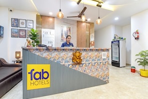 Uma área de recepção de hotel com design moderno, um recepcionista e um logotipo no balcão.
