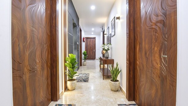 A hallway with wooden doors, potted plants, and a tiled floor. - Fabhotel Hari Residency (Haridwar)