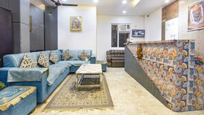 A living room with a blue sofa, a coffee table, and a patterned wall. - Fabhotel Hari Residency (Haridwar)