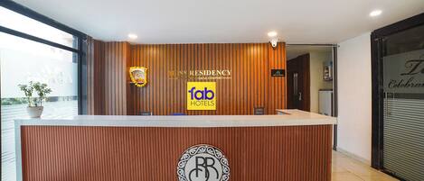 A reception desk with a wooden finish, a logo, and a sign for 'Fab Hotels'.