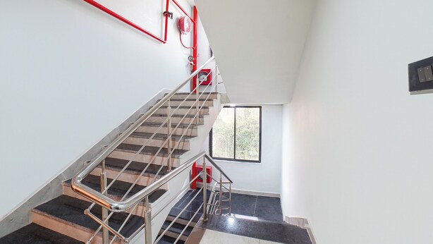 Een moderne trap met metalen leuningen en een rode brandslanghaspel aan de muur.