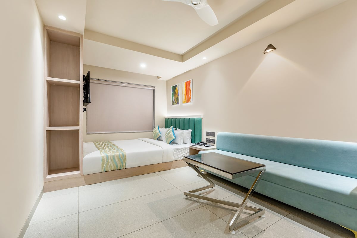 Una habitación de hotel moderna con una cama, un sofá, una mesita y un ventilador de techo.