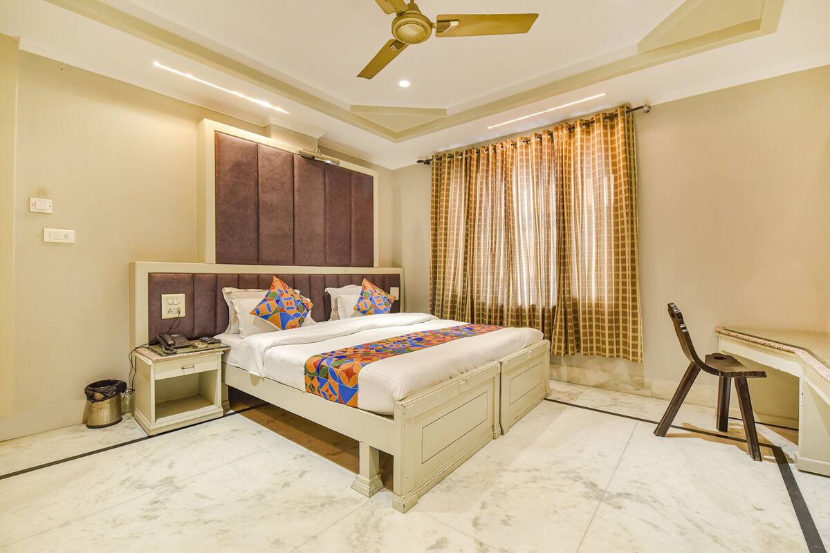 A bedroom with a bed, bedside table, nightstand, and a desk with a chair.
