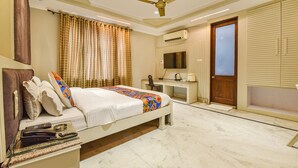 Una habitación de hotel con cama, escritorio, televisor y ventilador de techo.