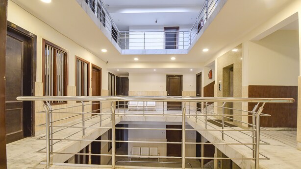 Un amplio vestíbulo de hotel de varios niveles, con suelo de mármol, barandillas de metal y una escalera central.