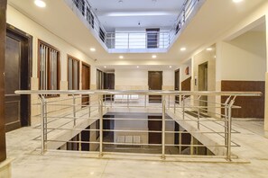 A spacious, multi-level hotel lobby with marble flooring, metal railings, and a central staircase.