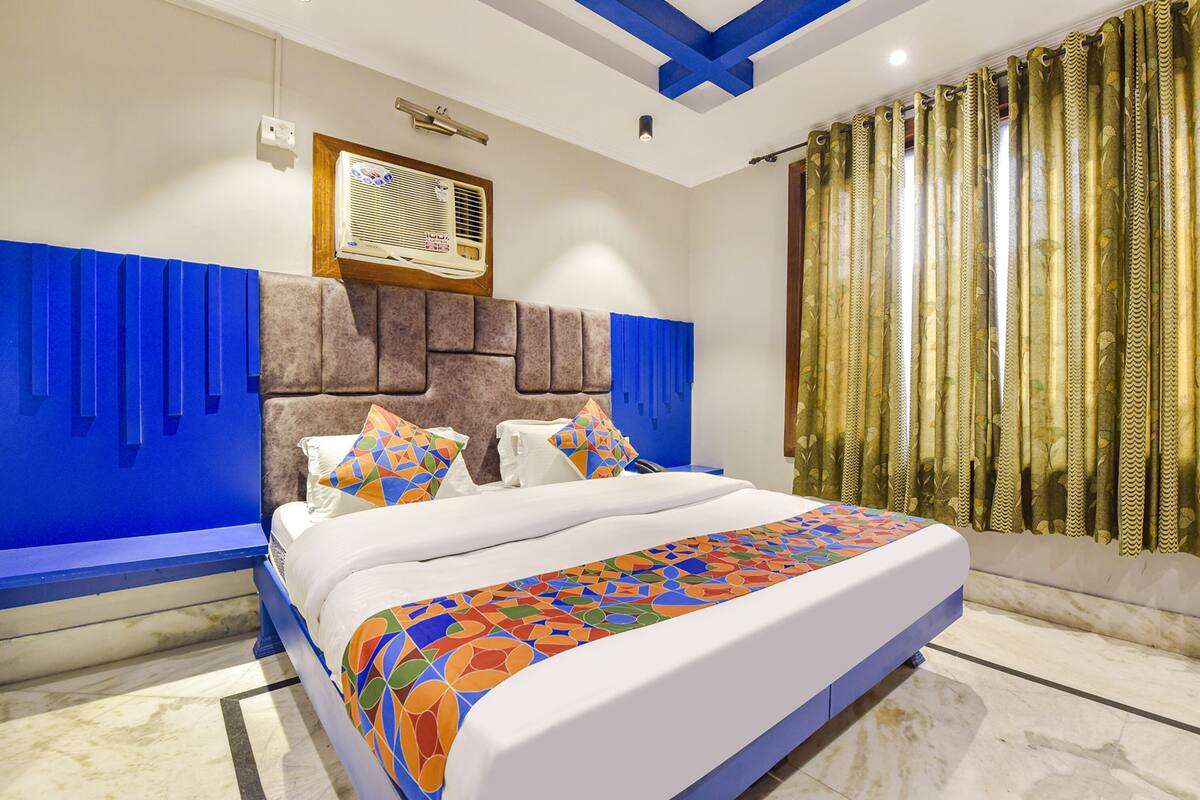 A modern bedroom with a large bed, blue accent walls, a decorative headboard, and a window with curtains.