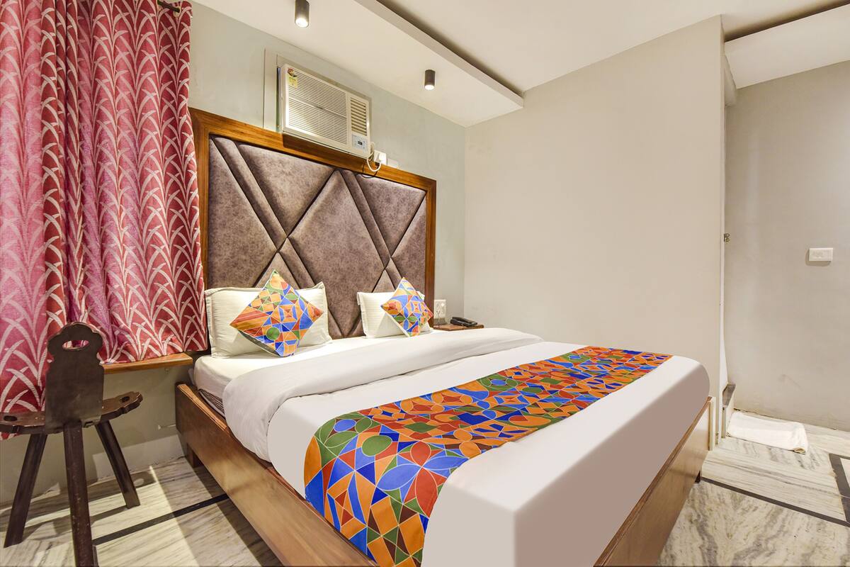 A hotel room with a bed, a headboard, a window, and a chair.
