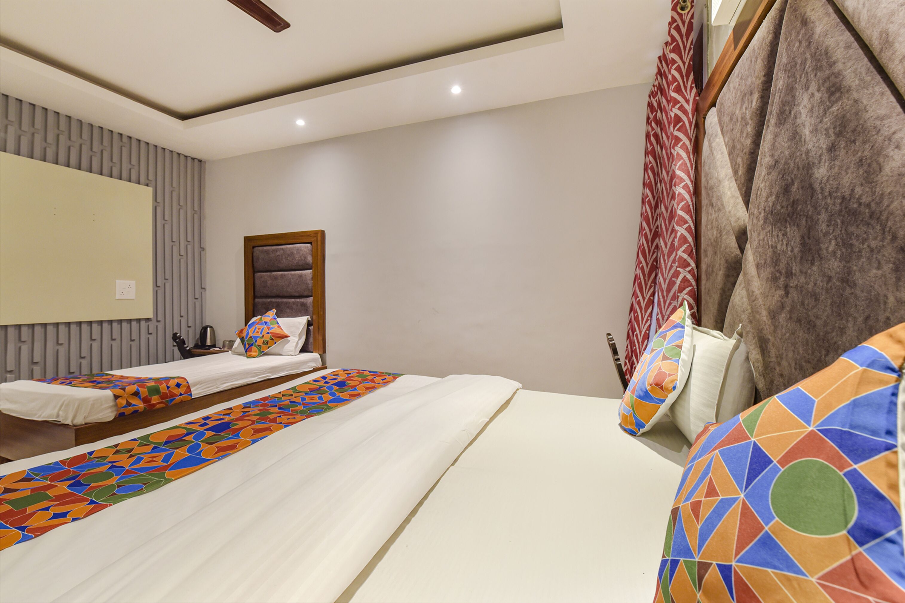 Una habitación de hotel con dos camas individuales y una cama grande, con cabecera.