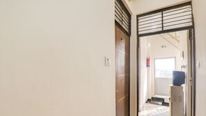A hallway with a door marked "10A" leading to a room with a television on a small cabinet. - Fabexpress City Inn (Faizabad)