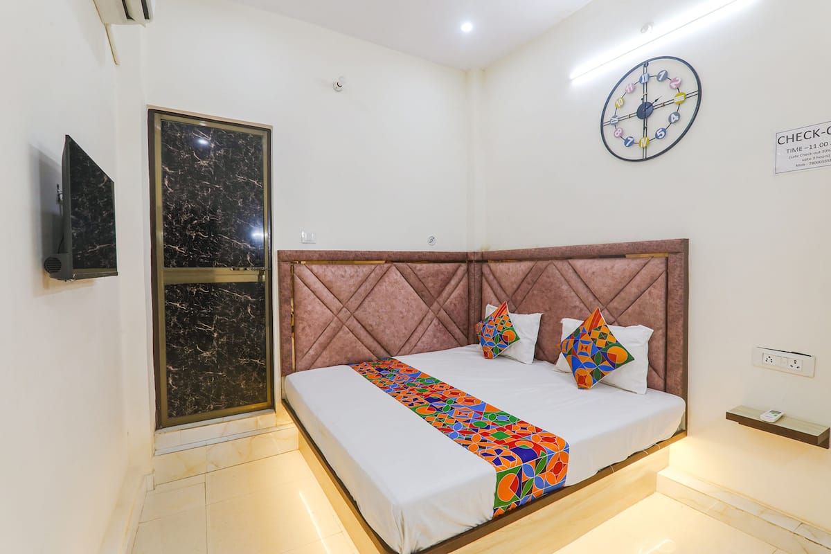 Une chambre d’hôtel avec un lit, une télévision, une horloge et un panneau indiquant l’heure limite de départ.