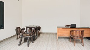 A room with a wooden desk, a laptop, and several chairs. - Hotel O Teluk Betung Near Water Park Lembah Hijau Formerly Kanajiwa Guesthouse 2 (Bandar Lampung)