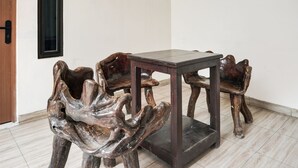 A dining table with a dark wooden top and matching chairs with a unique hand-shaped design. - Hotel O Teluk Betung Near Water Park Lembah Hijau Formerly Kanajiwa Guesthouse 2 (Bandar Lampung)