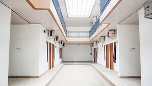 A spacious, multi-level atrium with a high ceiling and skylight, featuring a central open area and multiple doors leading to rooms. - Hotel O Teluk Betung Near Water Park Lembah Hijau Formerly Kanajiwa Guesthouse 2 (Bandar Lampung)