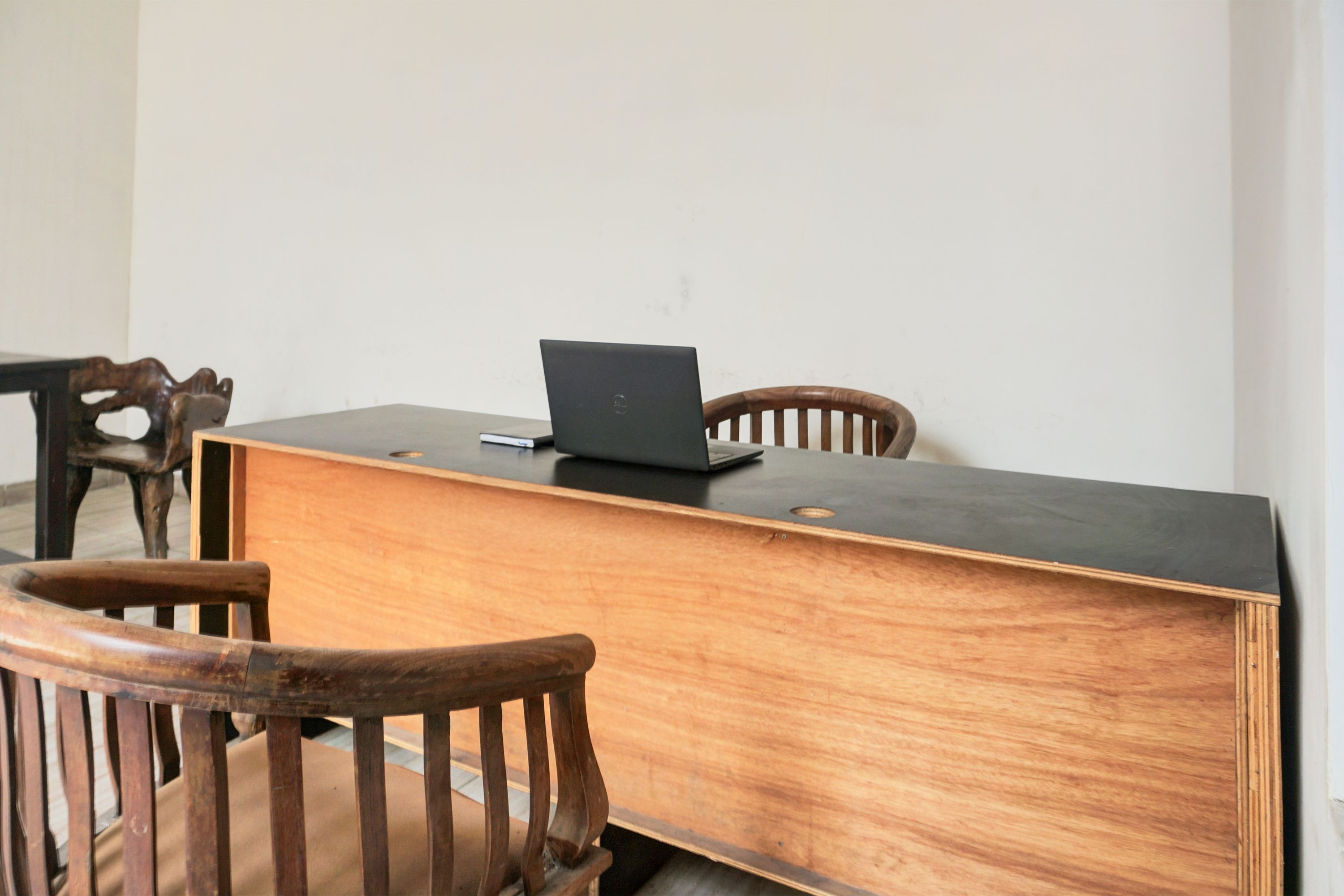 A wooden desk with a laptop, a chair, and a wooden table.