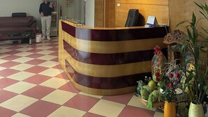 En hotellobby med en receptionsdisk i trä, klockor som visar tiden i New York, Tokyo, Paris och Hanoi, och en skylt för hotellet Truong Chiang.