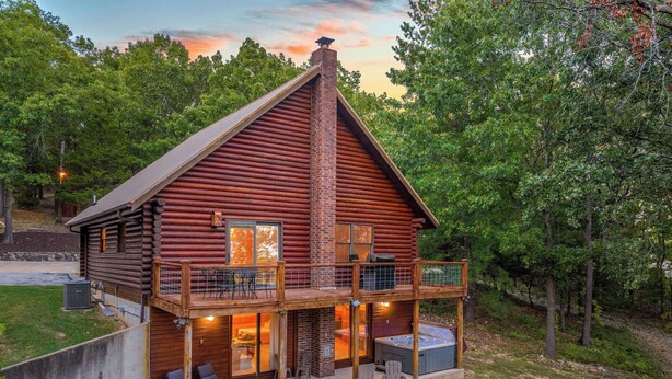 A log cabin with a deck, outdoor seating, and a fire pit.