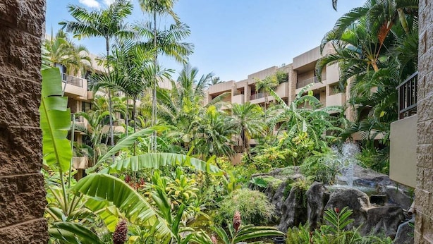 A lush indoor garden with a waterfall, surrounded by multi-story buildings with balconies.