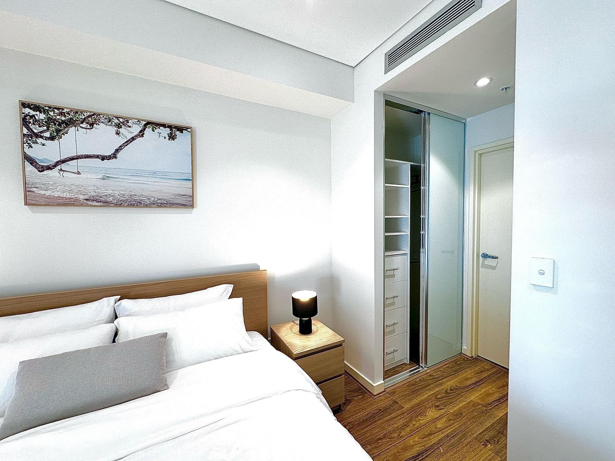 Quarto bem arrumado com cama, mesa de cabeceira e guarda-roupa com várias gavetas.