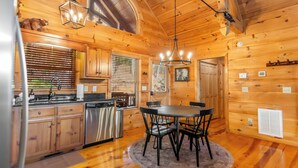 A wooden cabin interior with a kitchen, dining area, and a fireplace. - Mountain Views, Dog friendly, Fenced Yard, Barrel Sauna, Hot Tub, Fire Pit
 (Ellijay)