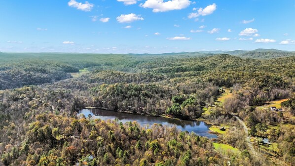 A panoramic view of a forested valley with a river, a small settlement, and distant hills.