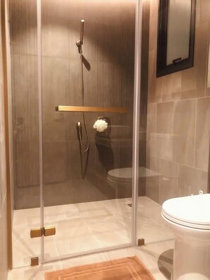 Cabina doccia in vetro con soffione a mano e rubinetto montato a parete.