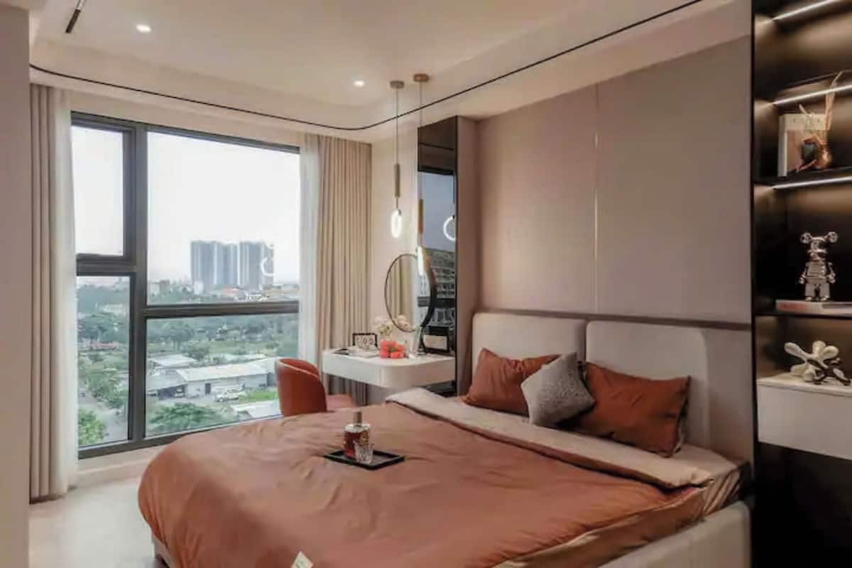 Ein modernes Schlafzimmer mit einem großen Bett, einem Nachttisch, einem Spiegel und Blick auf die Stadt.