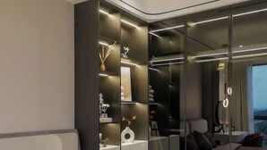 A modern bedroom with a bed, a bedside table with a bottle and flowers, and a large mirror reflecting the room. - The Antonia Apartments - Korea Town D7 (Ho Chi Minh City)