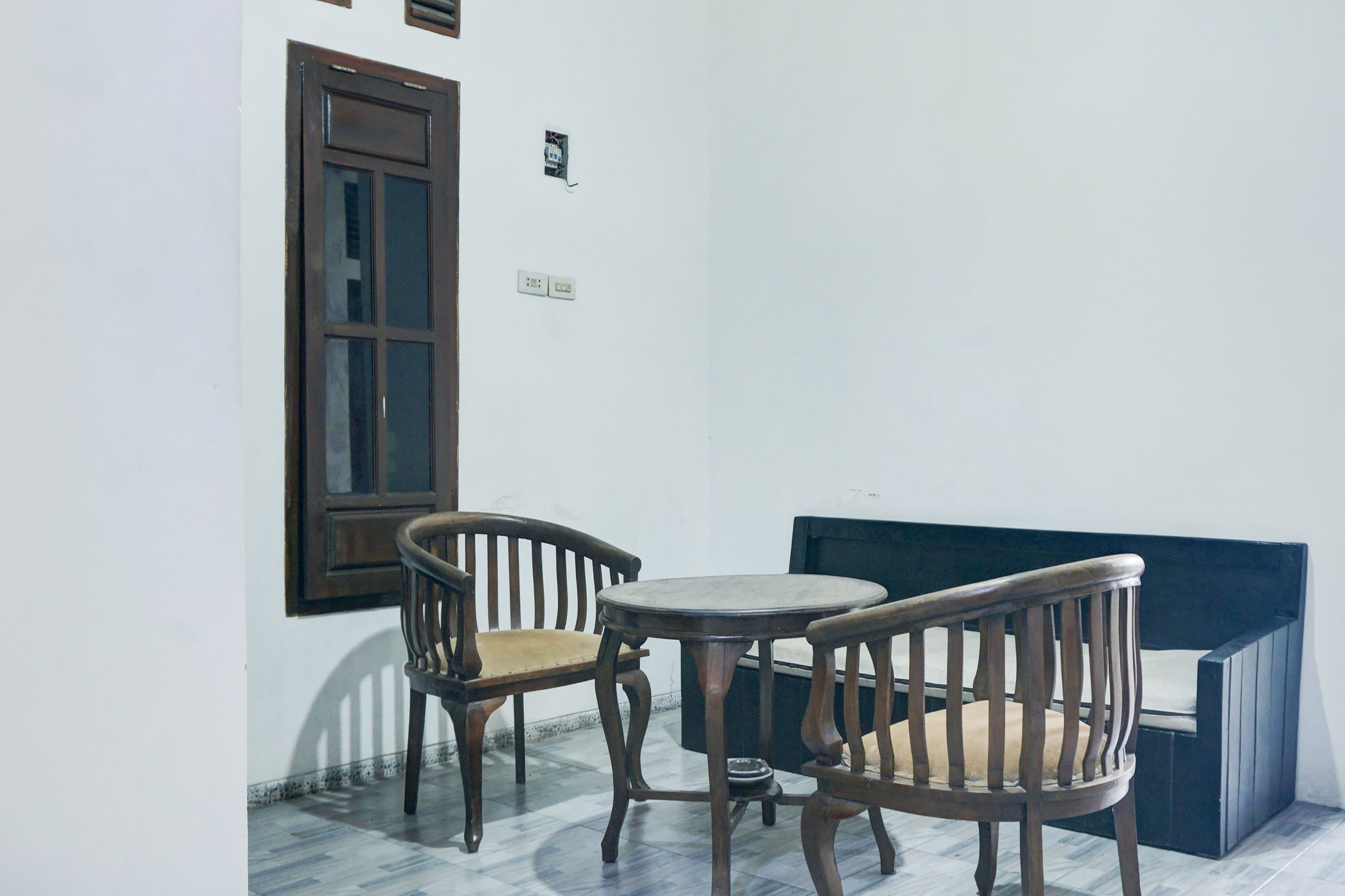 Una habitación pequeña con una mesa de madera y dos sillas, una ventana y un banco.