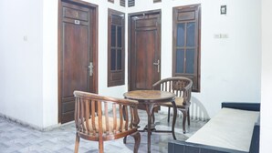 A room with three wooden doors, a small round table, and two wooden chairs.
