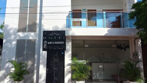 A hotel with a modern facade, a signboard for 'Hotel Santa Barbara', and a clear blue sky in the background. - Hotel Santa Bárbara Mompos (Mompos)