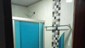 A bathroom with a blue shower enclosure, a white toilet, and a sink with a checkered tile backsplash. - Hotel Santa Bárbara Mompos (Mompos)