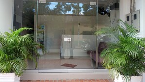 A modern building entrance with glass doors, a water dispenser, and potted plants. - Hotel Santa Bárbara Mompos (Mompos)