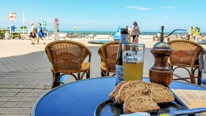 Een tafel met een fles Blanquette de Nantour, een glas geel drankje en sneetjes brood op een blauwe tafel.