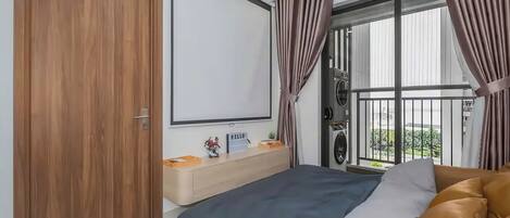 A bedroom with a bed, a wooden wardrobe, a bedside table with a 'HELLO' sign, and a balcony with curtains.