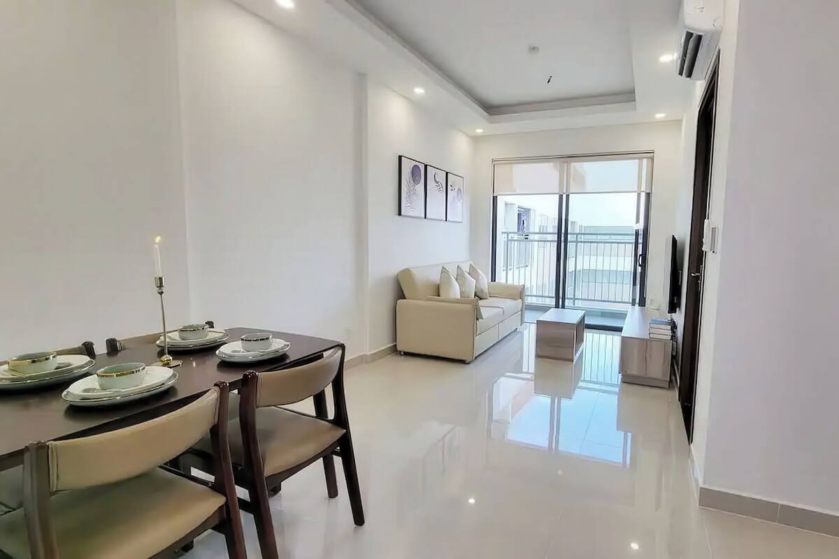 A modern apartment with a dining area, a living room with a sofa, and a kitchen.