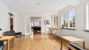A spacious room with a wooden floor, a dining table, a sofa, and a window with a view of trees. - "Garbine" - 1.5km from the sea by Interhome (Østermarie)