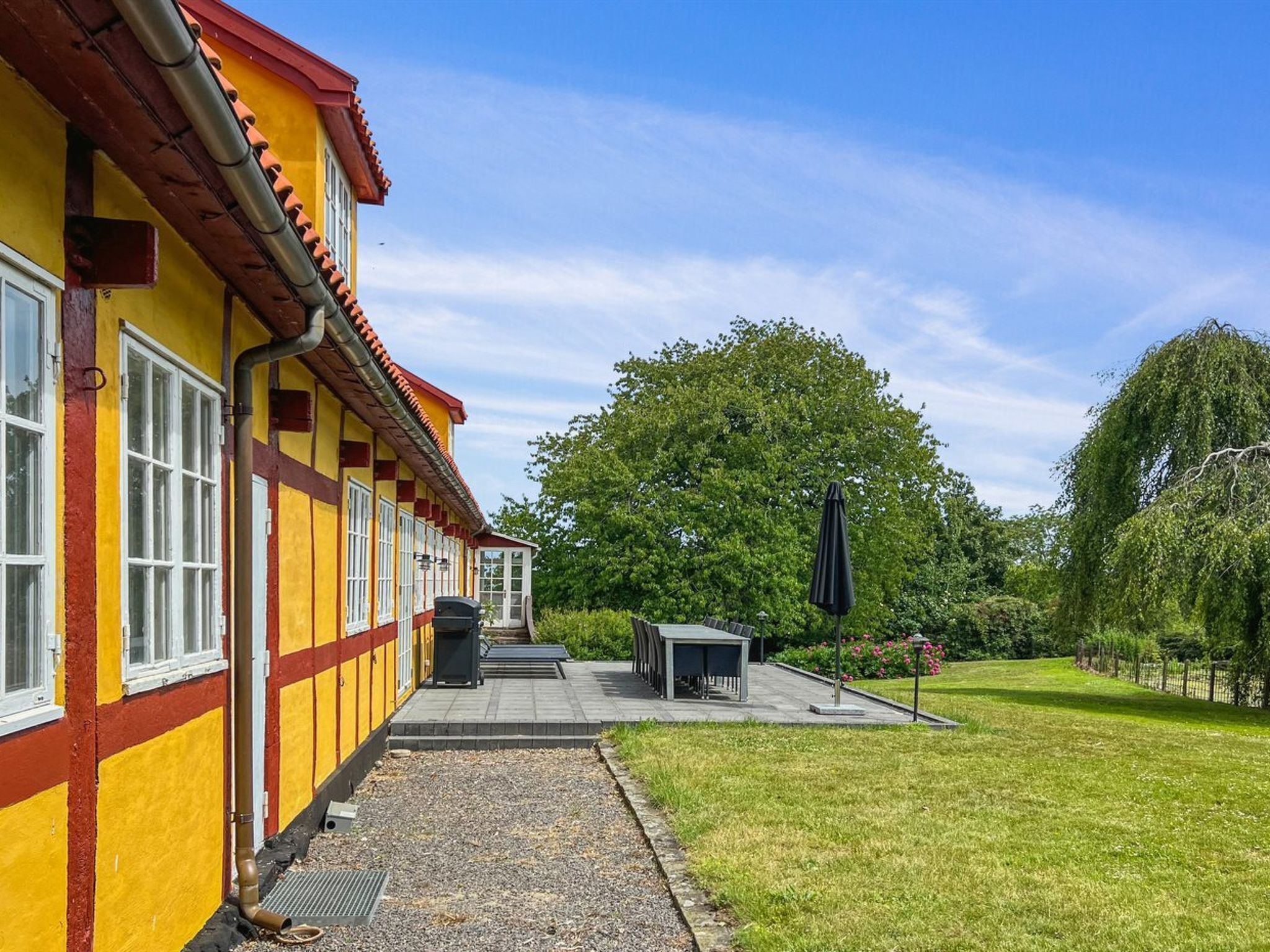 A yellow building with red accents, a covered outdoor seating area, and a well-maintained lawn.
