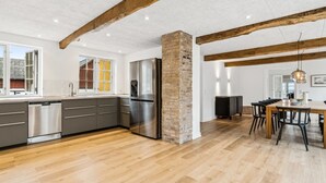 A modern kitchen with a large island, stainless steel appliances, and a dining area with a wooden table and chairs. - "Garbine" - 1.5km from the sea by Interhome (Østermarie)