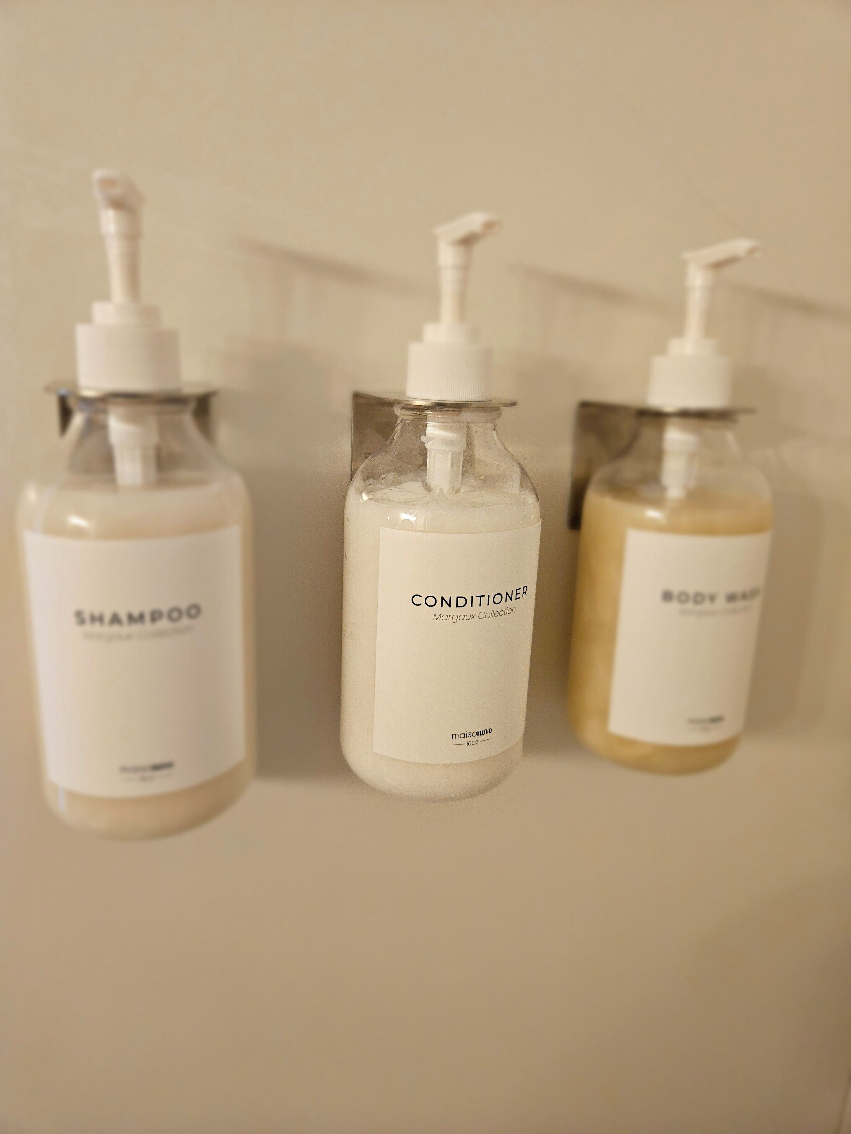 Three bottles of shampoo, conditioner, and body wash on a bathroom counter.