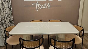 A dining area with a table and chairs, a wall with 'LBK Texas' written on it, and a patterned curtain. - Isolated King bed, 2 Queen beds - Fenced yard - 9 min to Texas Tech (Lubbock)
