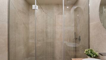 Un baño moderno con ducha de vidrio, tocador de madera y lavamanos blanco.