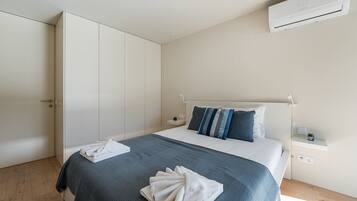 Une chambre à coucher comprenant un lit, une armoire, une table de chevet et un appareil de climatisation.
