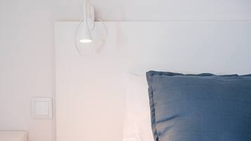 A bedroom with a white headboard, a blue pillow, and a wall-mounted light fixture.