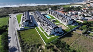 Ein Küstenhotel mit langem, rechteckigem Gebäude, einem Schwimmbad und einer angrenzenden Straße.